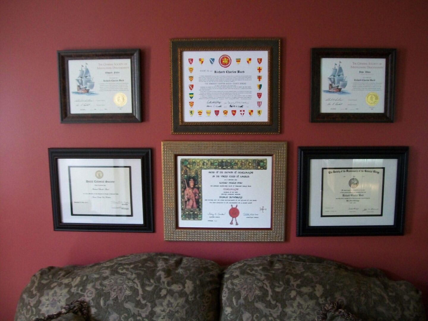A wall displaying six framed certificates and awards above a couch.