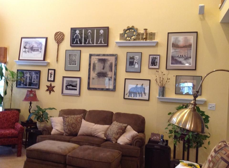 Living room wall filled with framed photos and art above a brown sofa.